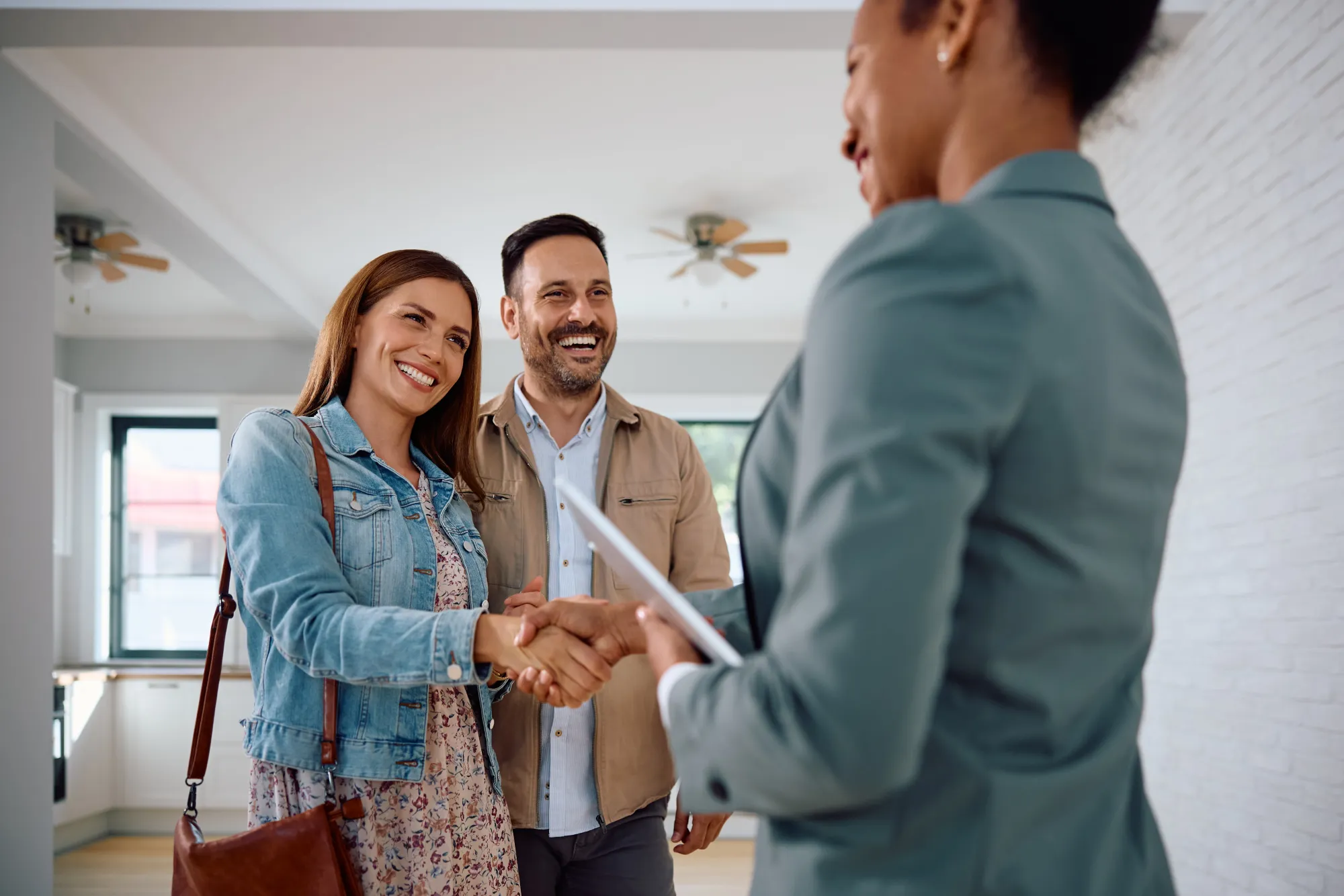 An agent shaking hands with buyers in a new apartment